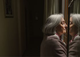 Starija žena usamljeno gleda kroz prozor negativan primer